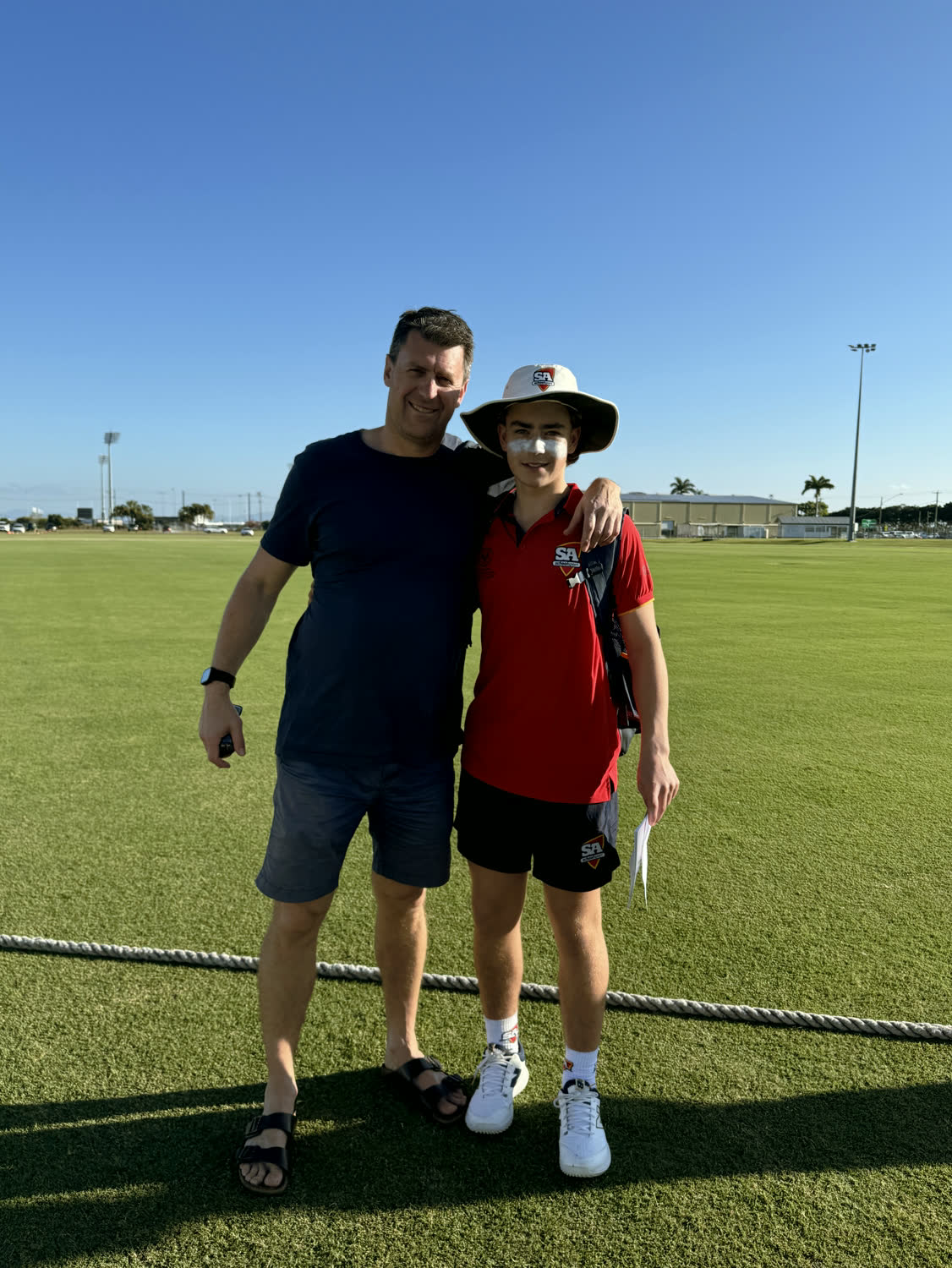 Rob Gregory at the boundary rope with a junior pathway cricketer